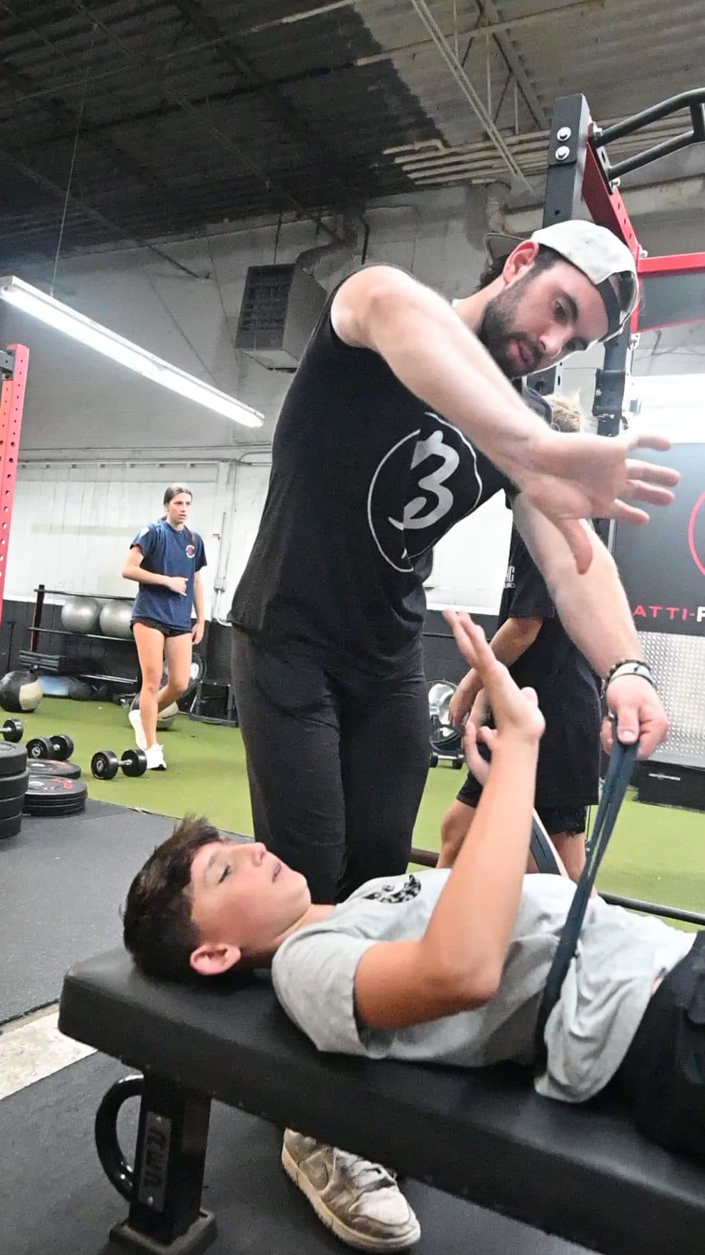 Batti coach adjusting an athlete's wrist during a band press on the bench