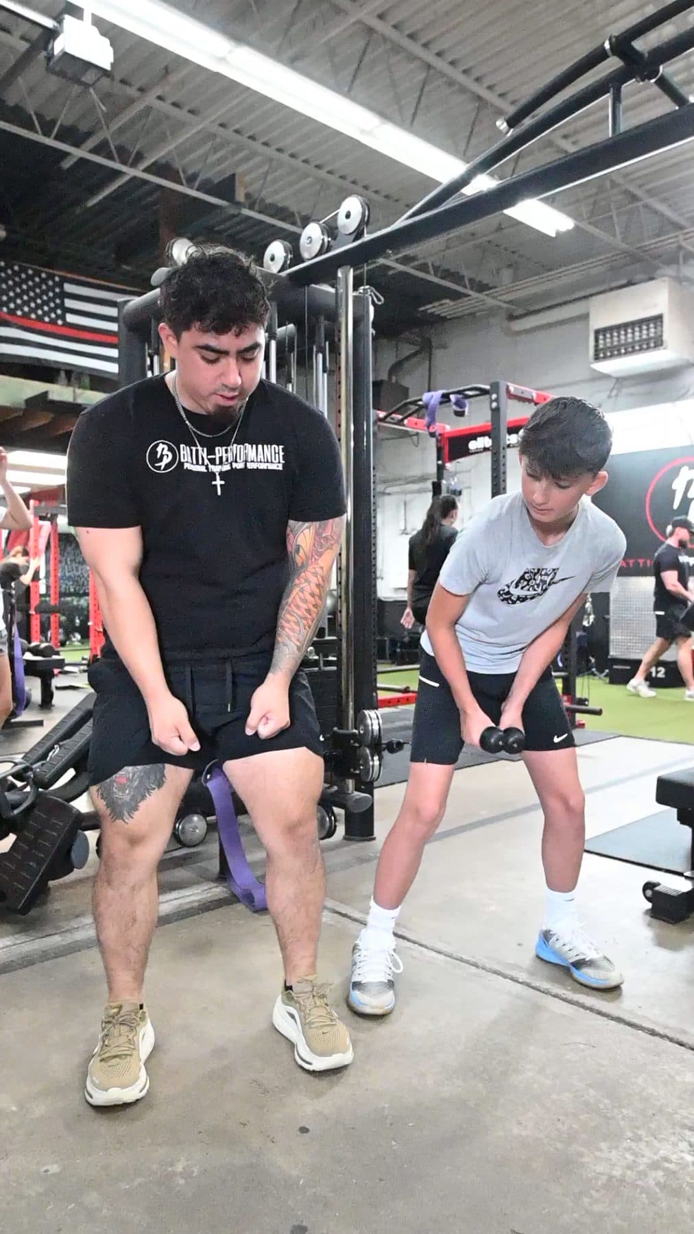 Batti coach demonstrating a hip hinge side by side with an athlete