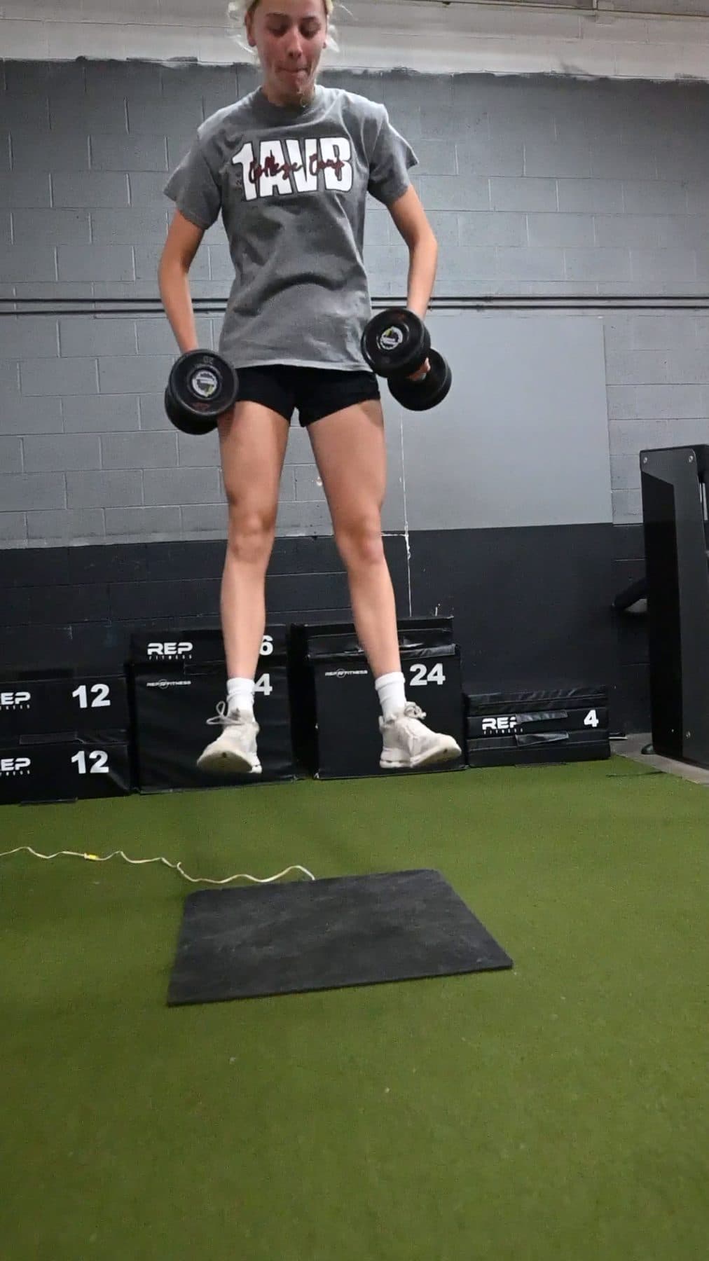 Athlete airborne in a dumbbell squat jump on the jump mat