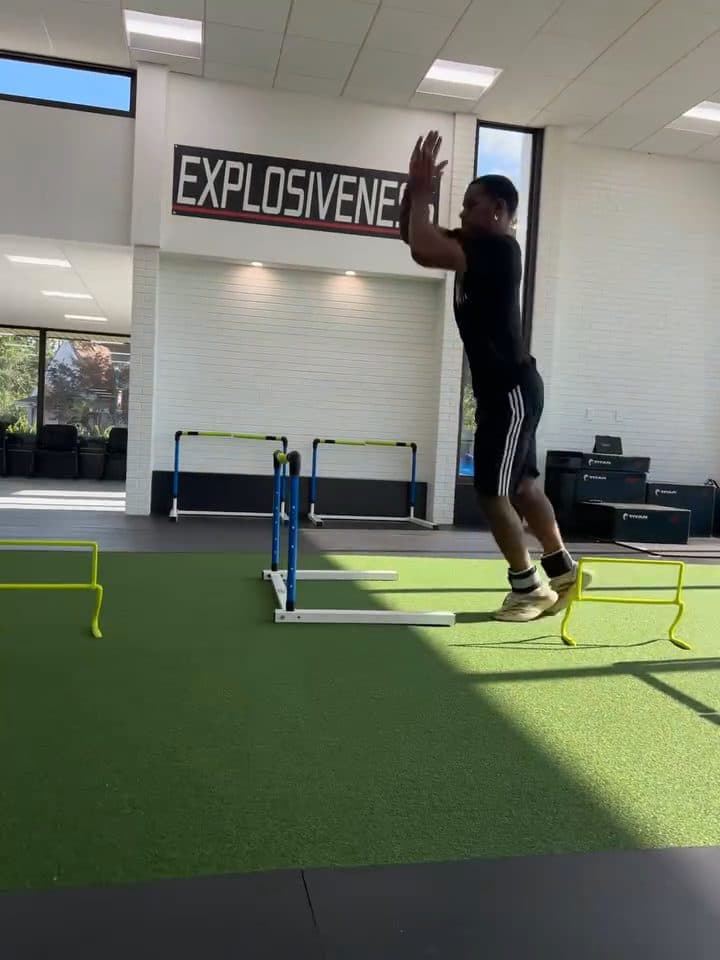 Athlete airborne over a hurdle during continuous hurdle hops