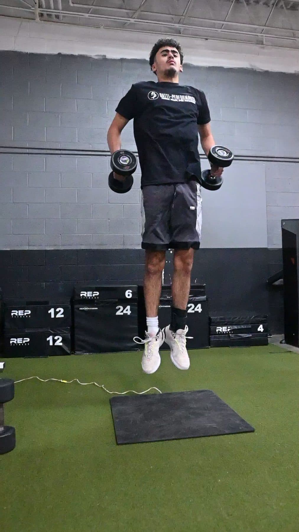 Athlete in a dumbbell squat jump on the jump mat